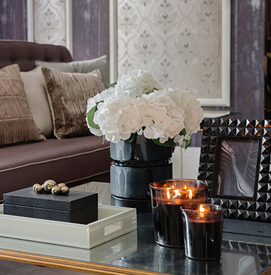 Modern kitchen featuring dark cabinetry, a marble countertop, gas stove, and large fridge, with herringbone flooring.