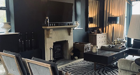 a cozy living room setup featuring two beige armchairs with a small side table holding a cup, complemented by light-colored curtains and a bookshelf in the background, perfect for modern interior design.