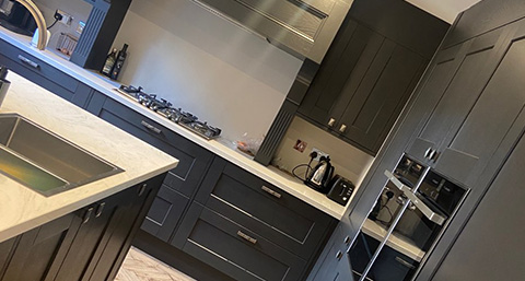 modern kitchen with dark cabinetry and marble countertop, featuring gas stove and various kitchen appliances